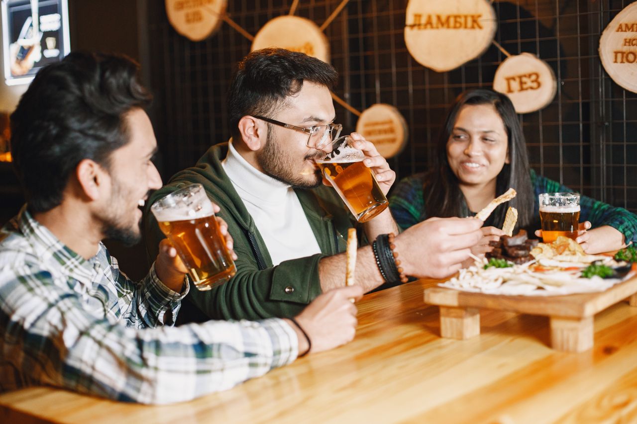 our-experience Friends at a pub sharing drinks and snacks, smiling and socializing.
